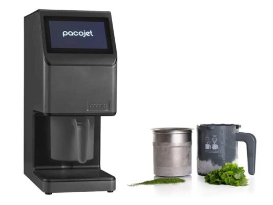 Chef che utilizza un Pacojet 4 in una cucina professionale con bicchieri di prodotto surgelato e Kit Fresco in evidenza.